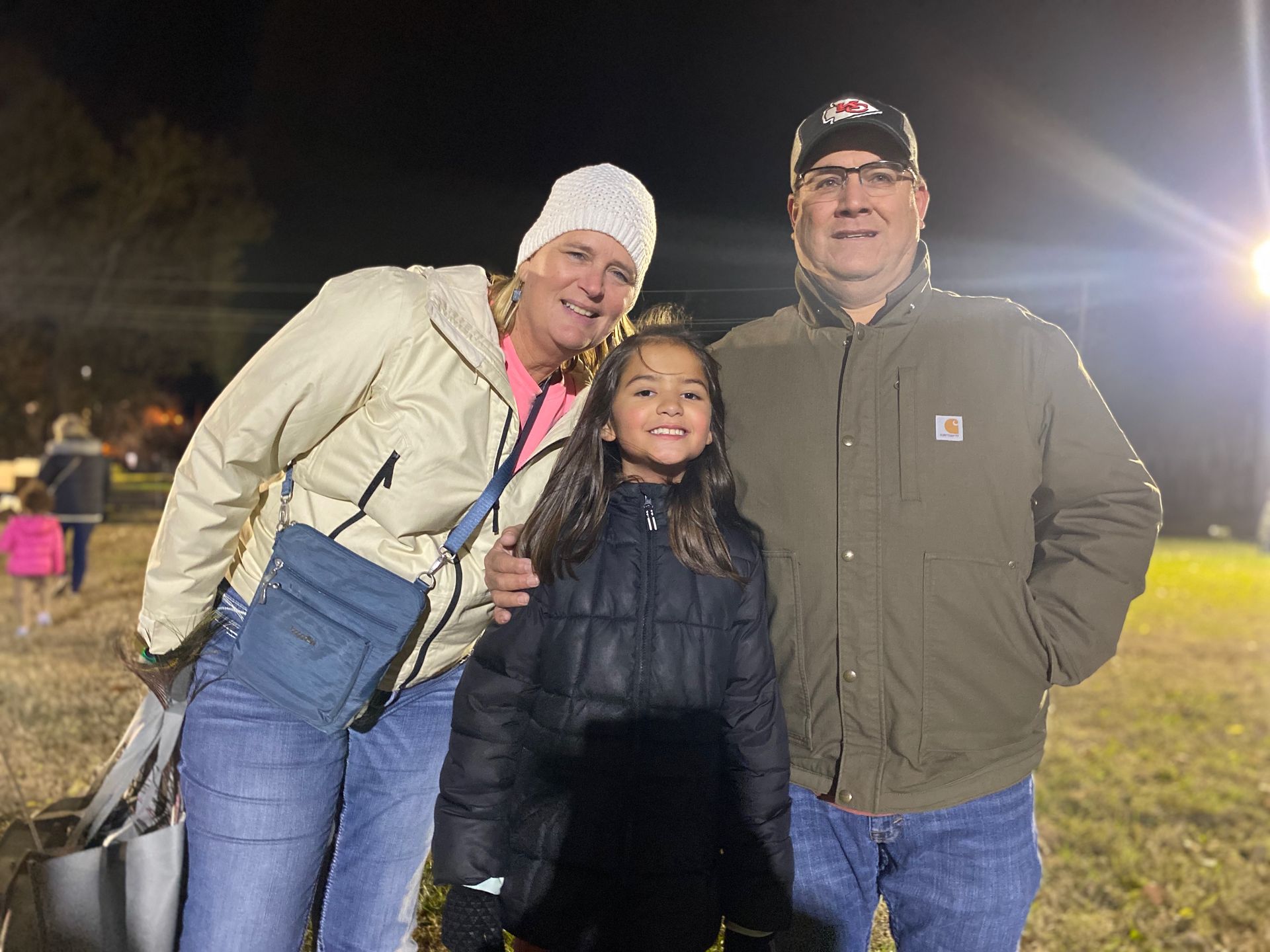 A man , woman and child are posing for a picture in a field at night.