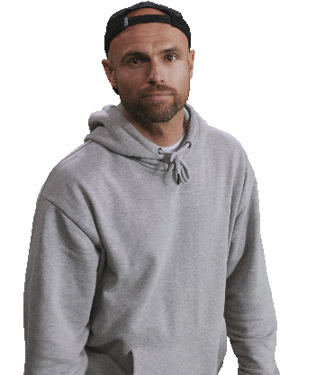Man wearing a gray hoodie and black cap looking at the camera.