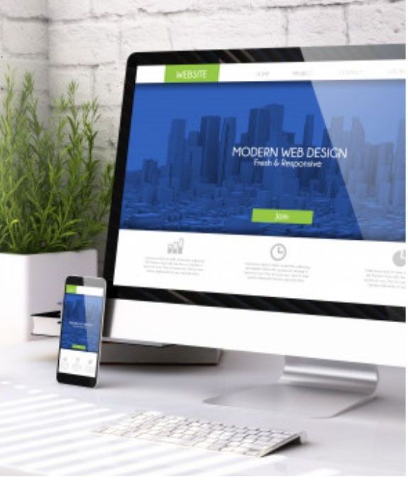 Desktop computer and smartphone displaying a website design on a desk with a plant in the background.