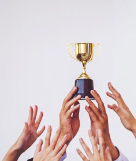 Hands reaching up toward a gold trophy against a white background.