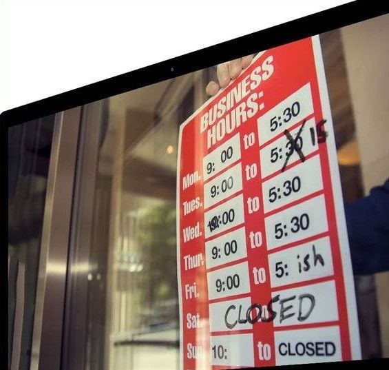 A person holding a business hours sign, crossed-out time, and closed sign.