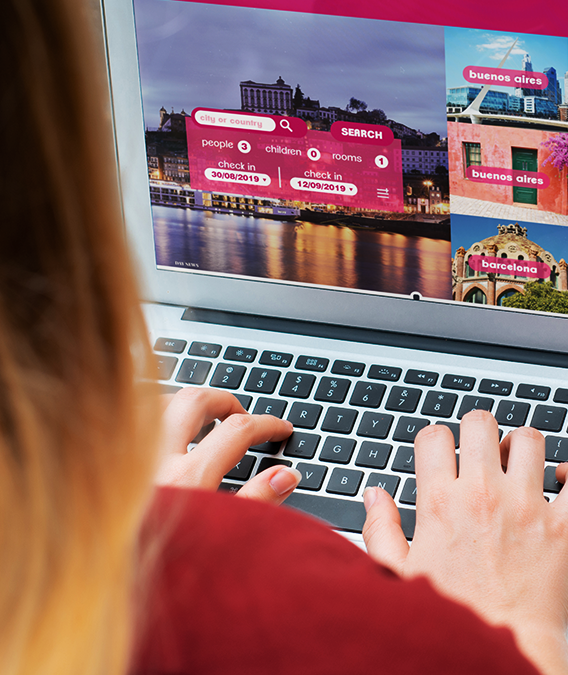 Person using a laptop, typing; travel website displayed, searching for locations.