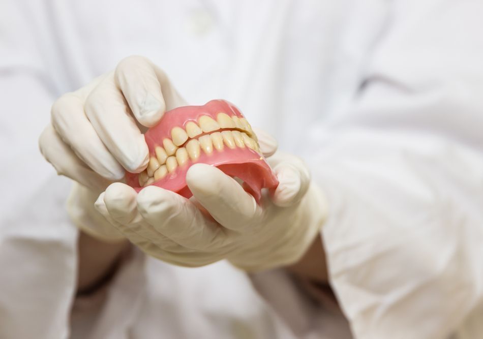 A Dentist Is Holding A Model Of Teeth In His Hands — Dentures Direct Taree-Rod Hinton In Taree, NSW