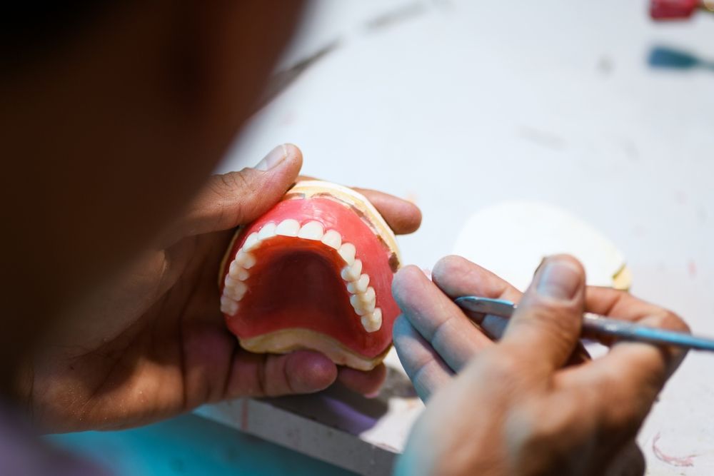 A Dentist Is Working On A Model Of A Person 's Teeth — Dentures Direct Taree-Rod Hinton In Taree, NSW
