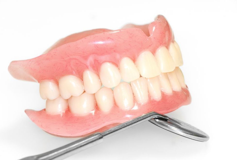 A Denture Is Sitting On Top Of A Dental Mirror — Dentures Direct Taree-Rod Hinton In Taree, NSW