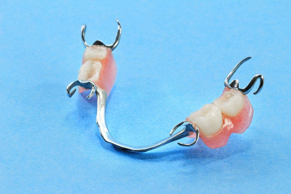 A Close Up Of A Denture On A Blue Surface — Dentures Direct Taree-Rod Hinton In Port Macquarie, NSW