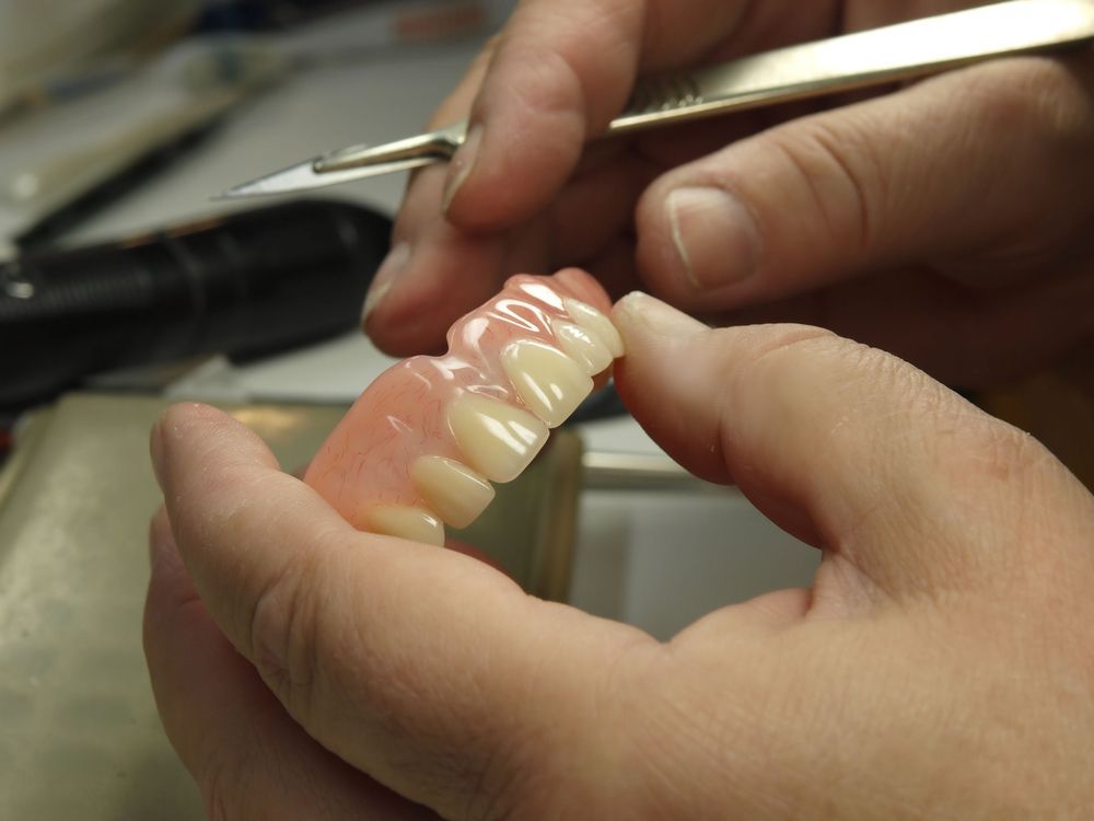 A person is working on a denture — Dentures Direct Taree-Rod Hinton In Taree, NSW