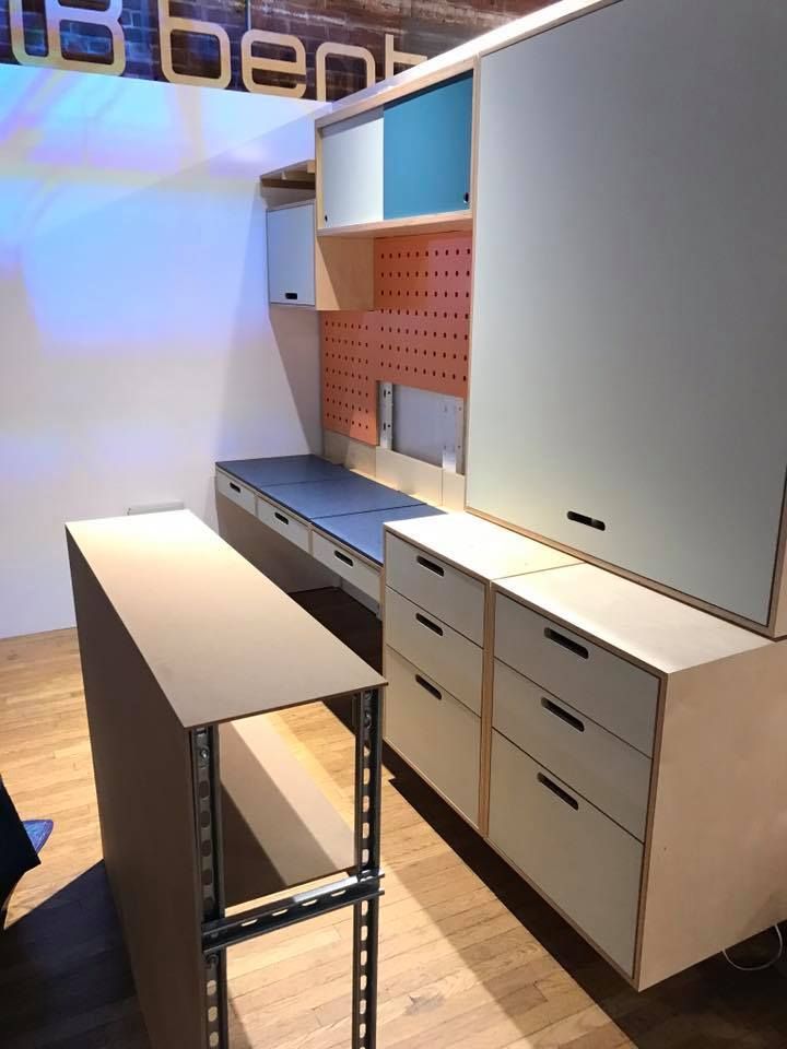 Modern workspace with desk, drawers, shelves, and pegboard in various colors.