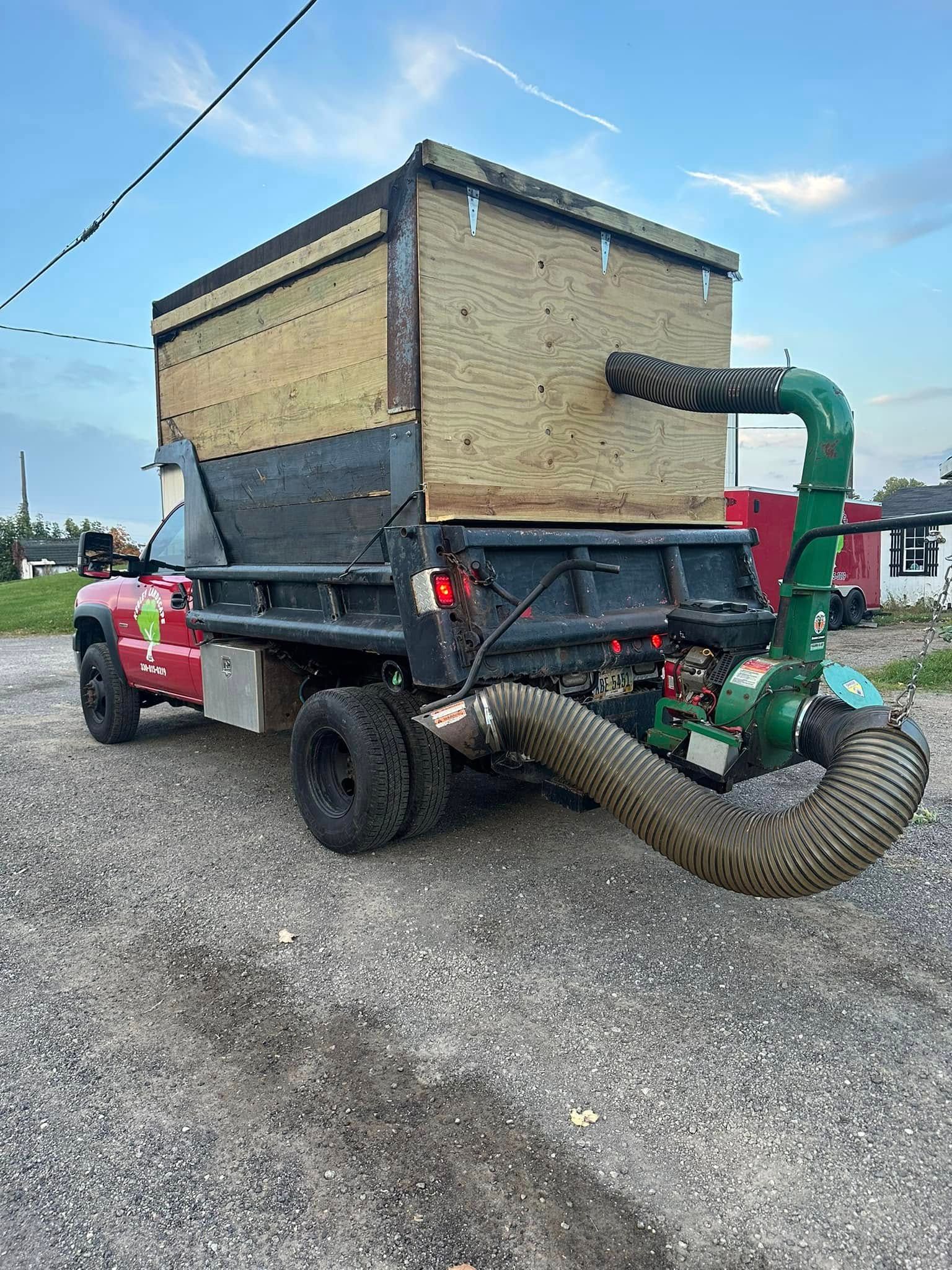 Red truck with a large vacuum trailer and hose on a gravel lot under a blue sky