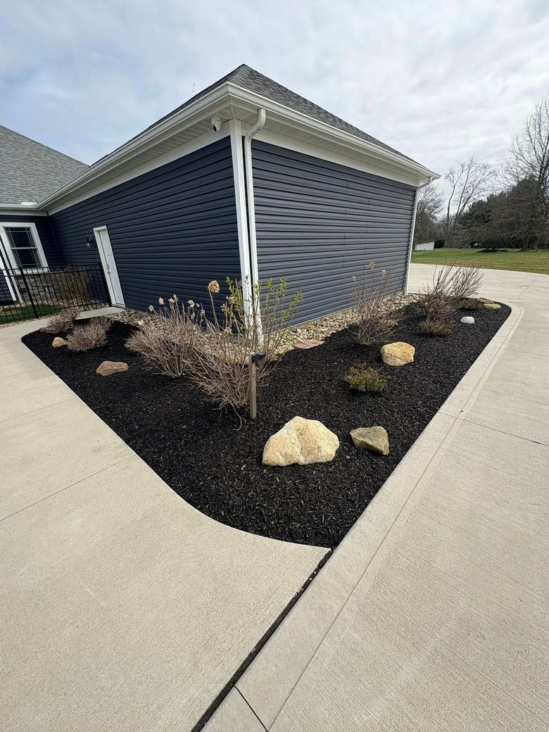 Basement window well with white trim and gravel outside a house wall