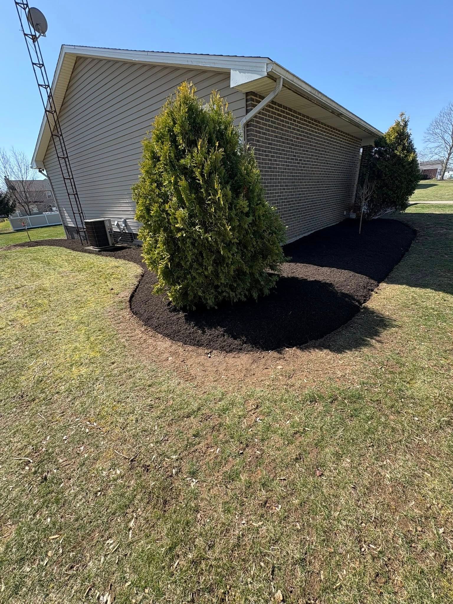 Damaged house with a collapsed front porch roof, partially hidden by a small shrub on a sunny lawn