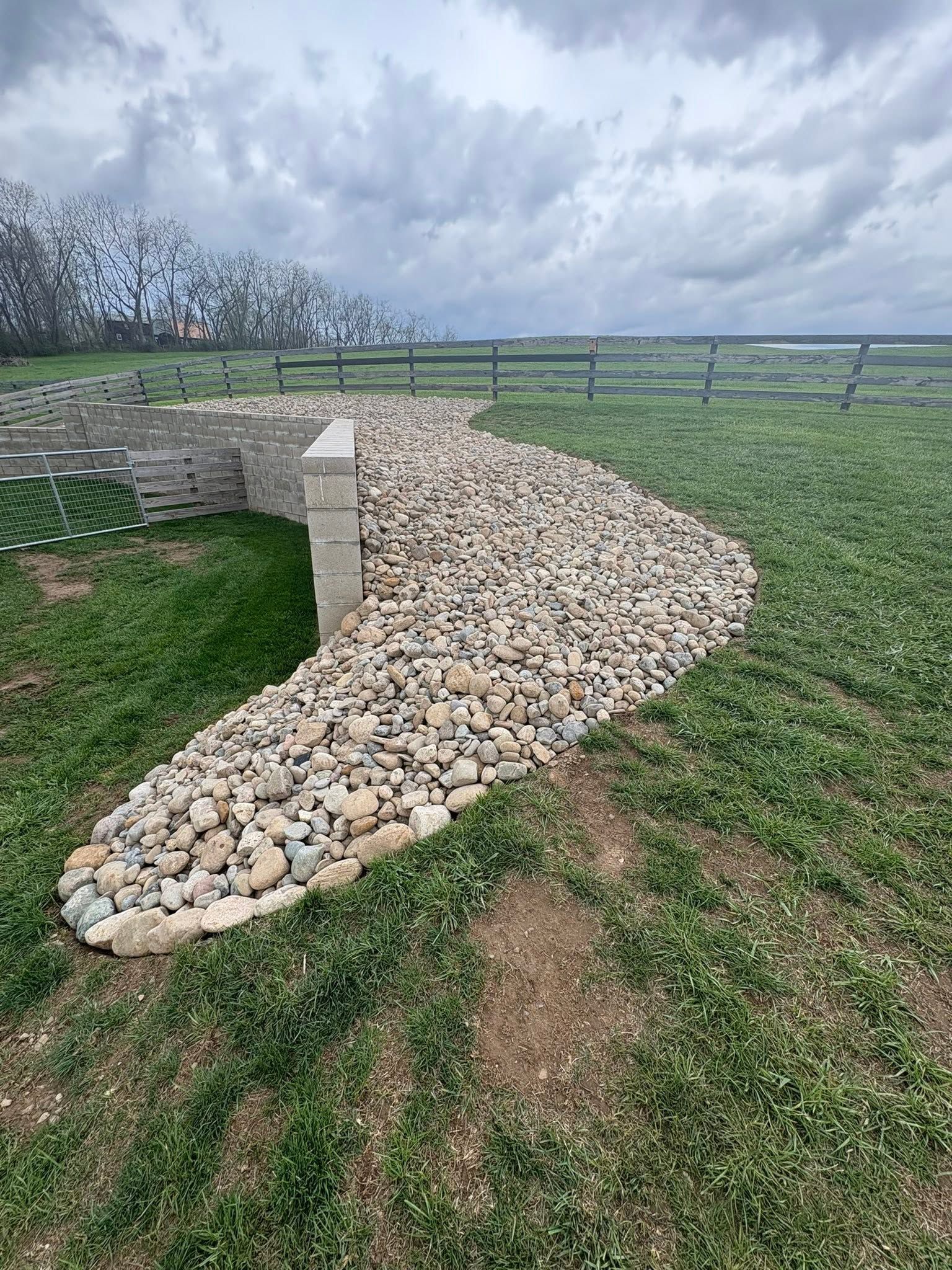 Curved white rock garden border beside green grass under a cloudy sky
