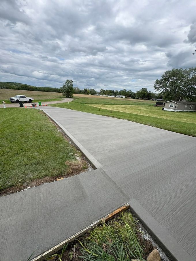Curved concrete walkway through a grassy park under a cloudy sky