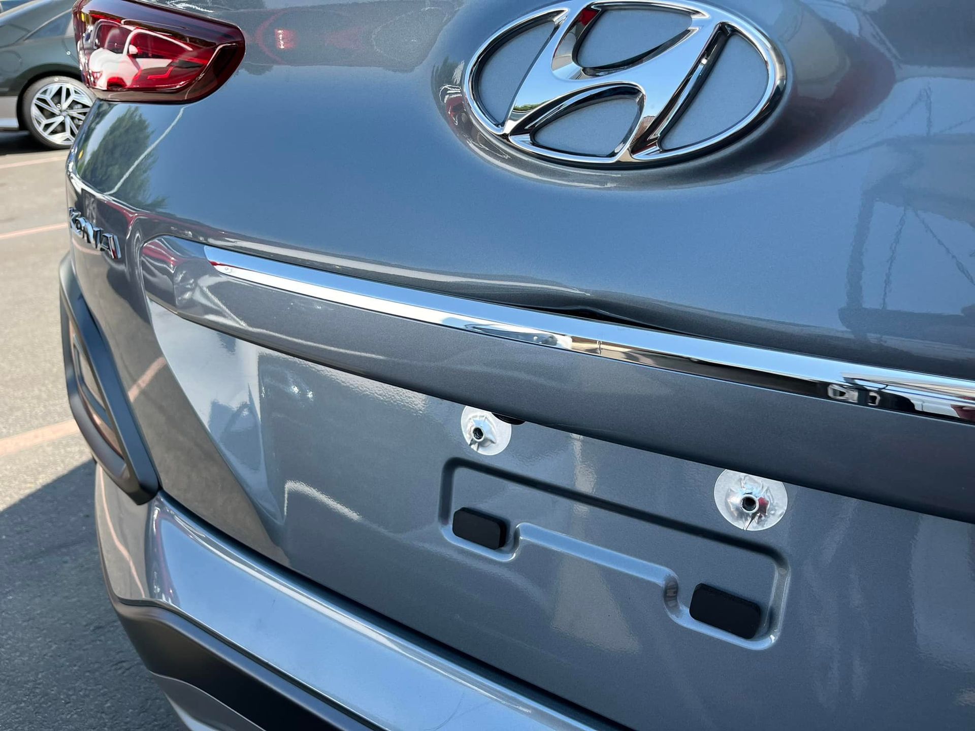 The gray rear trunk of a Hyundai vehicle featuring a chrome trim piece and two empty license plate mounting holes.
