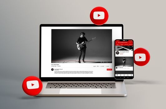 Ein Laptop und ein Smartphone, auf denen ein YouTube-Video zu sehen ist, umgeben von roten Wiedergabesymbolen.