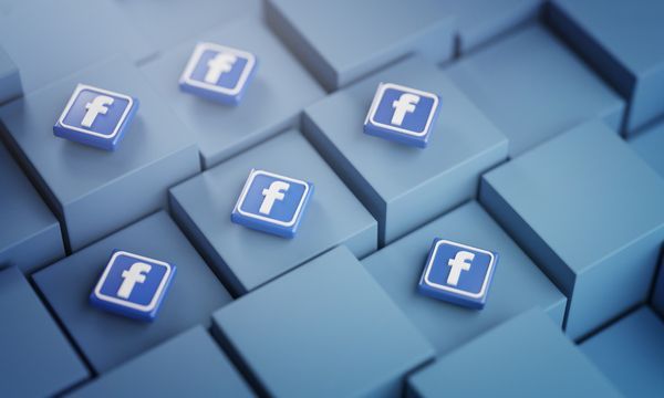 Kleine Facebook-Logos auf blauen 3D-Würfeln, die in einem Raster angeordnet sind.