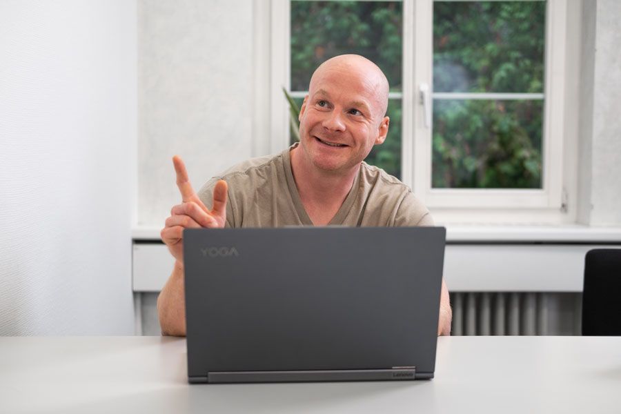 Ein Mann sitzt an einem Tisch vor einem Laptop.