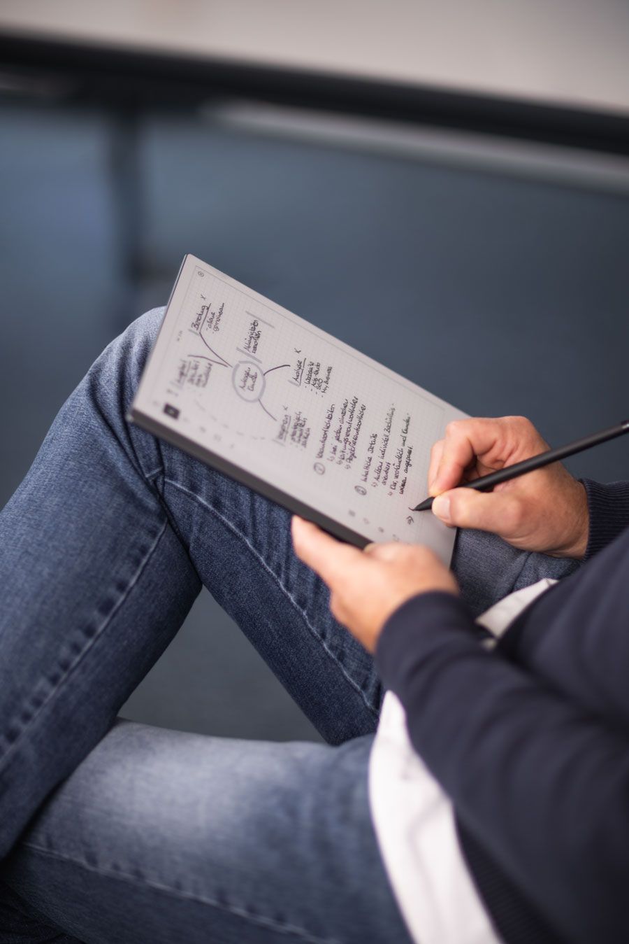 Eine Frau hält ein Blatt Papier vor einen Laptop.