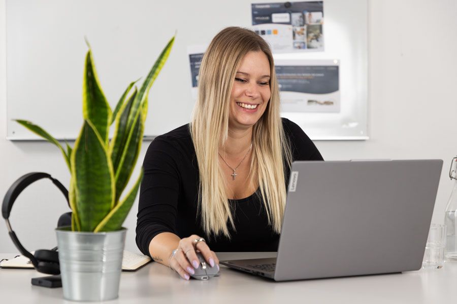 Eine Frau sitzt an einem Schreibtisch und benutzt einen Laptop.