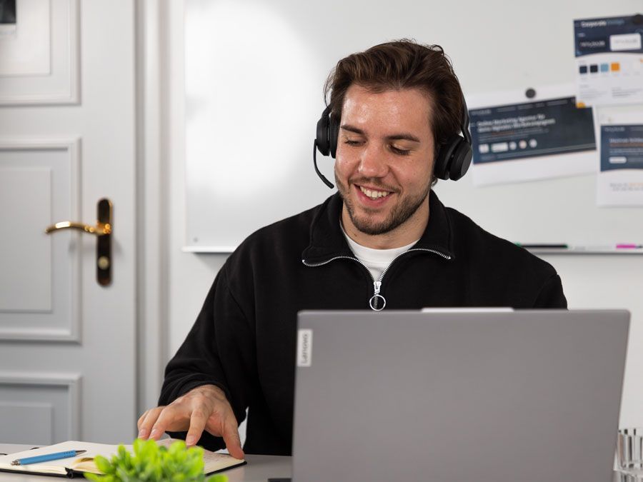 Eine Frau hält ein Blatt Papier vor einen Laptop.