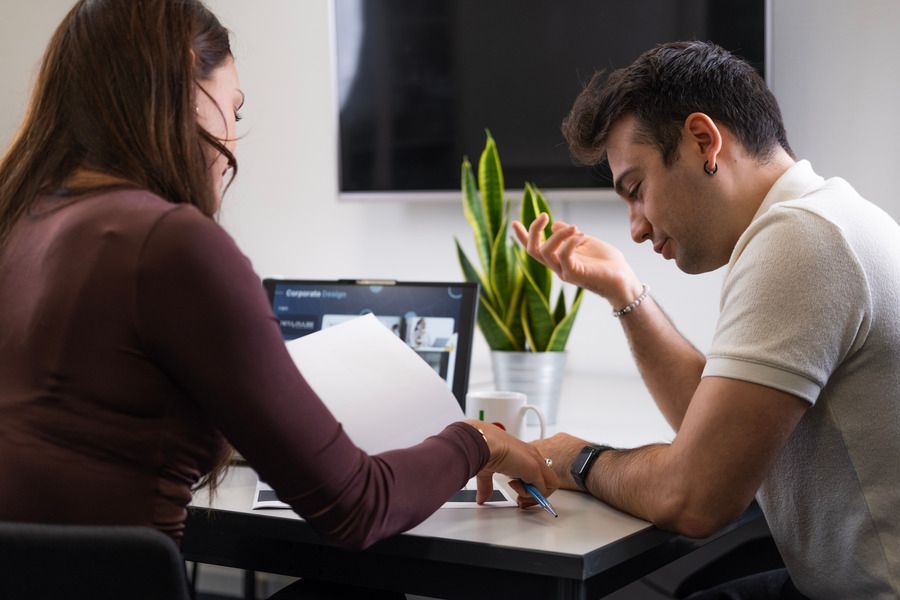 Eine Frau hält ein Blatt Papier vor einen Laptop.
