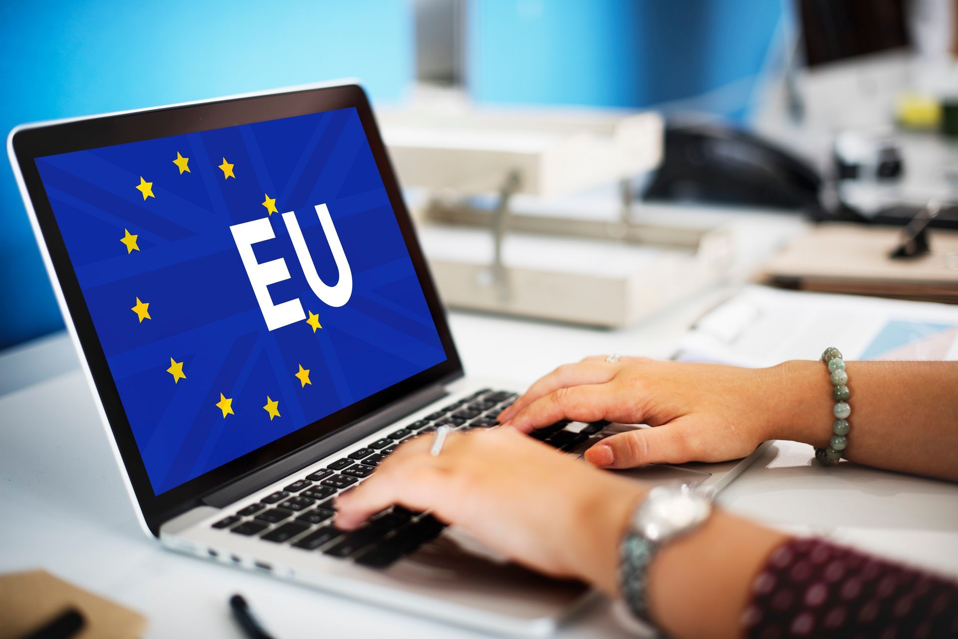 Eine Perso tippt auf einen Laptop, worauf das Eu Logo zusehen ist.