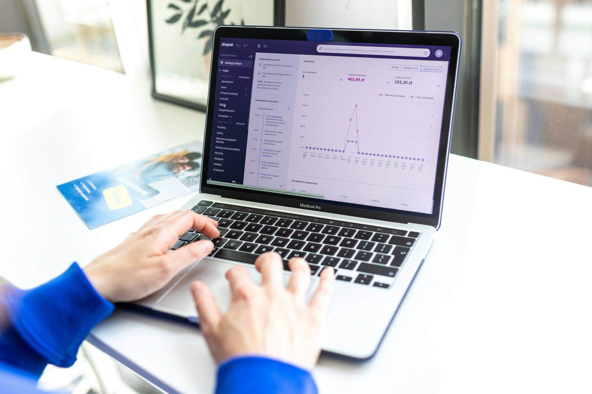 Person tippt auf einem MacBook Pro, auf dem ein E-Commerce-Dashboard mit Verkaufsanalysen geöffnet ist.