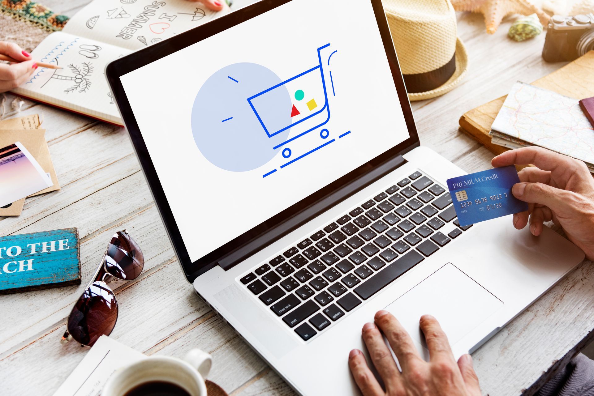 Eine Person hält eine Kreditkarte vor einen Laptop-Computer.