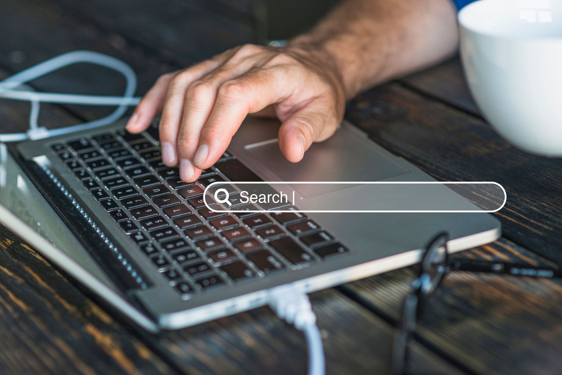Eine Person tippt auf einem Laptop, während eine Google-Suchseite geöffnet ist.