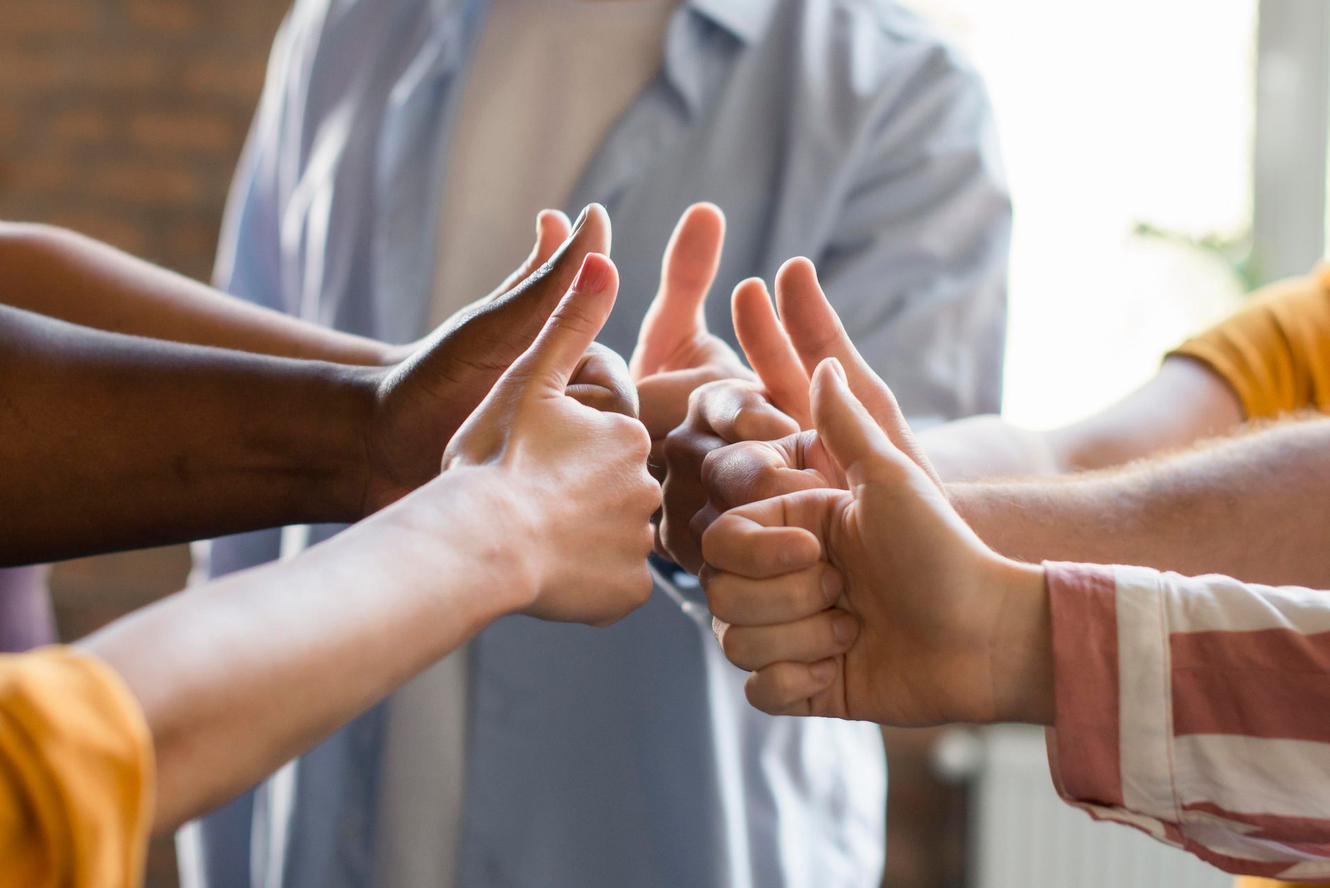 Eine Gruppe von Menschen drückt sich die Hände und zeigt den Daumen nach oben.