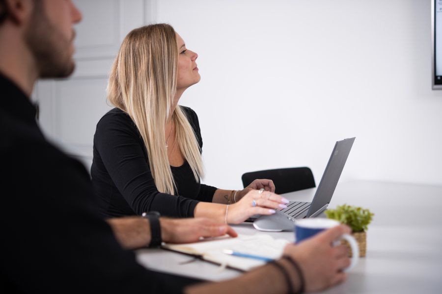 Eine Frau hält ein Blatt Papier vor einen Laptop.