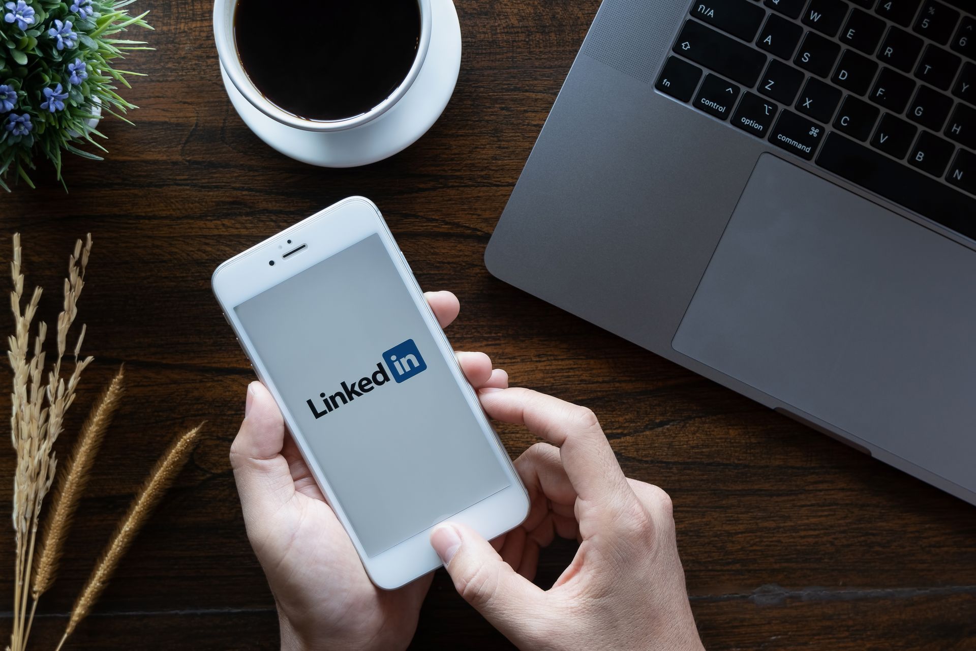Eine Person hält ein Mobiltelefon mit dem LinkedIn-Logo in der Hand.