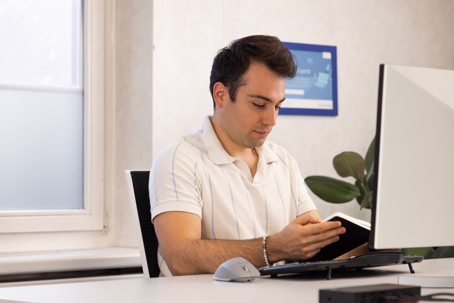 Ein Mann im weissen Hemd steht vor einem Laptop.