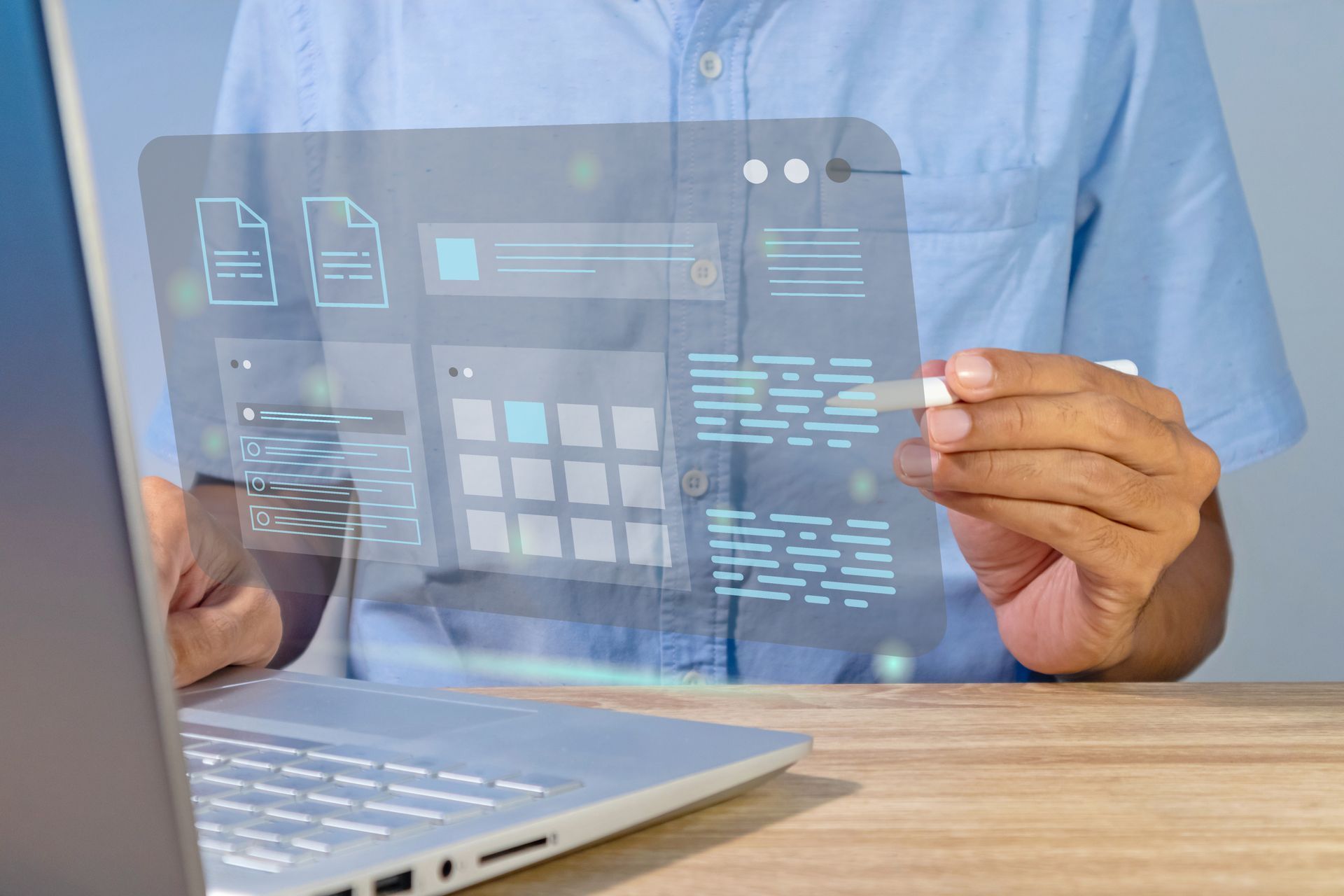 Eine Person, die einen Laptop mit einer transparenten digitalen Benutzeroberfläche benutzt, auf der Diagramme und Symbole angezeigt werden.