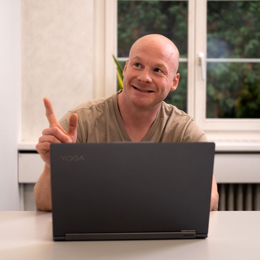 A man is sitting in front of a laptop that says yoga