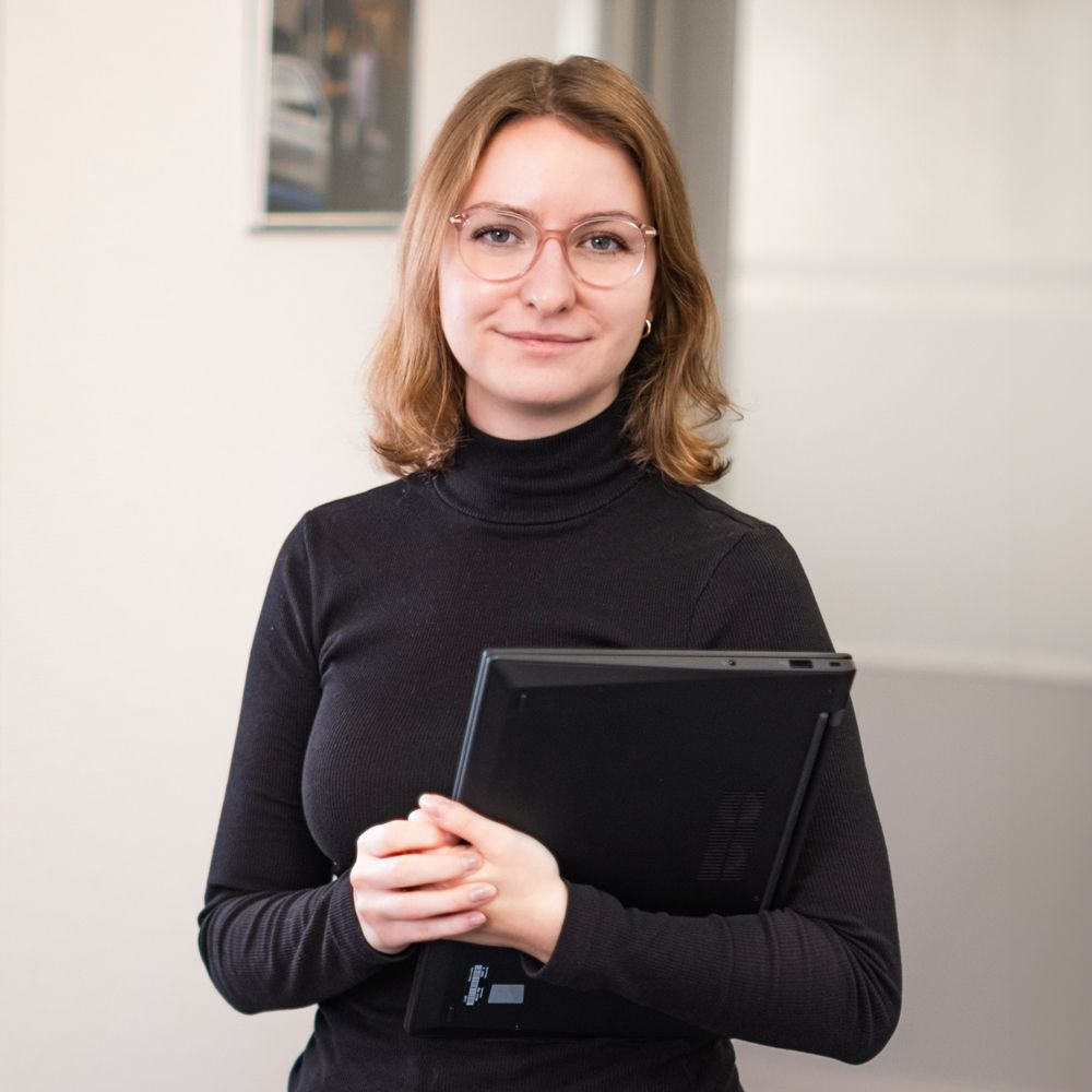 Eine Frau sitzt an einem Tisch und benutzt einen Laptop.
