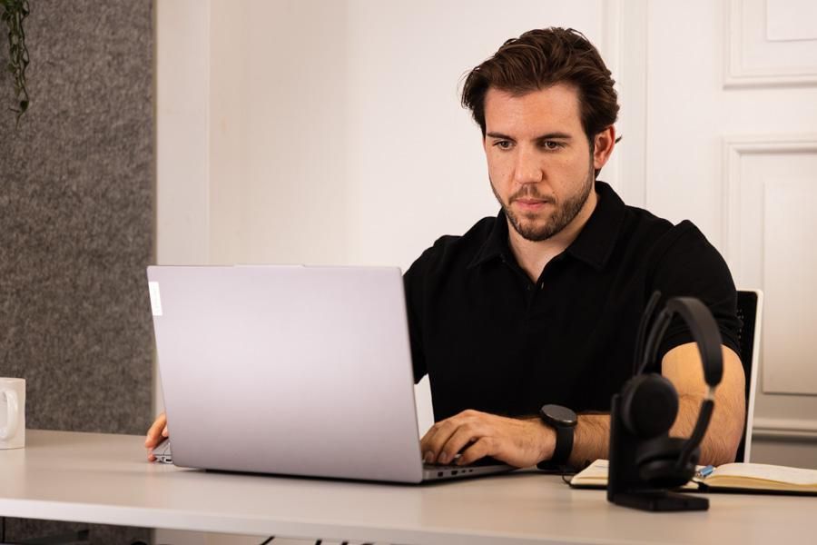 Ein Mann sitzt konzentriert an einem Laptop und arbeitet.