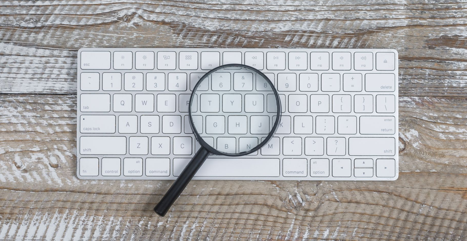Eine Lupe auf einer weissen Tastatur.