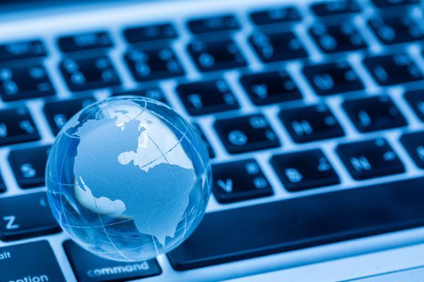 Blauer Globus auf einer Laptop-Tastatur, der das Internet oder globale Vernetzung symbolisiert.
