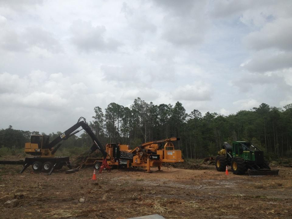 A group of construction vehicles are parked in a dirt field.
