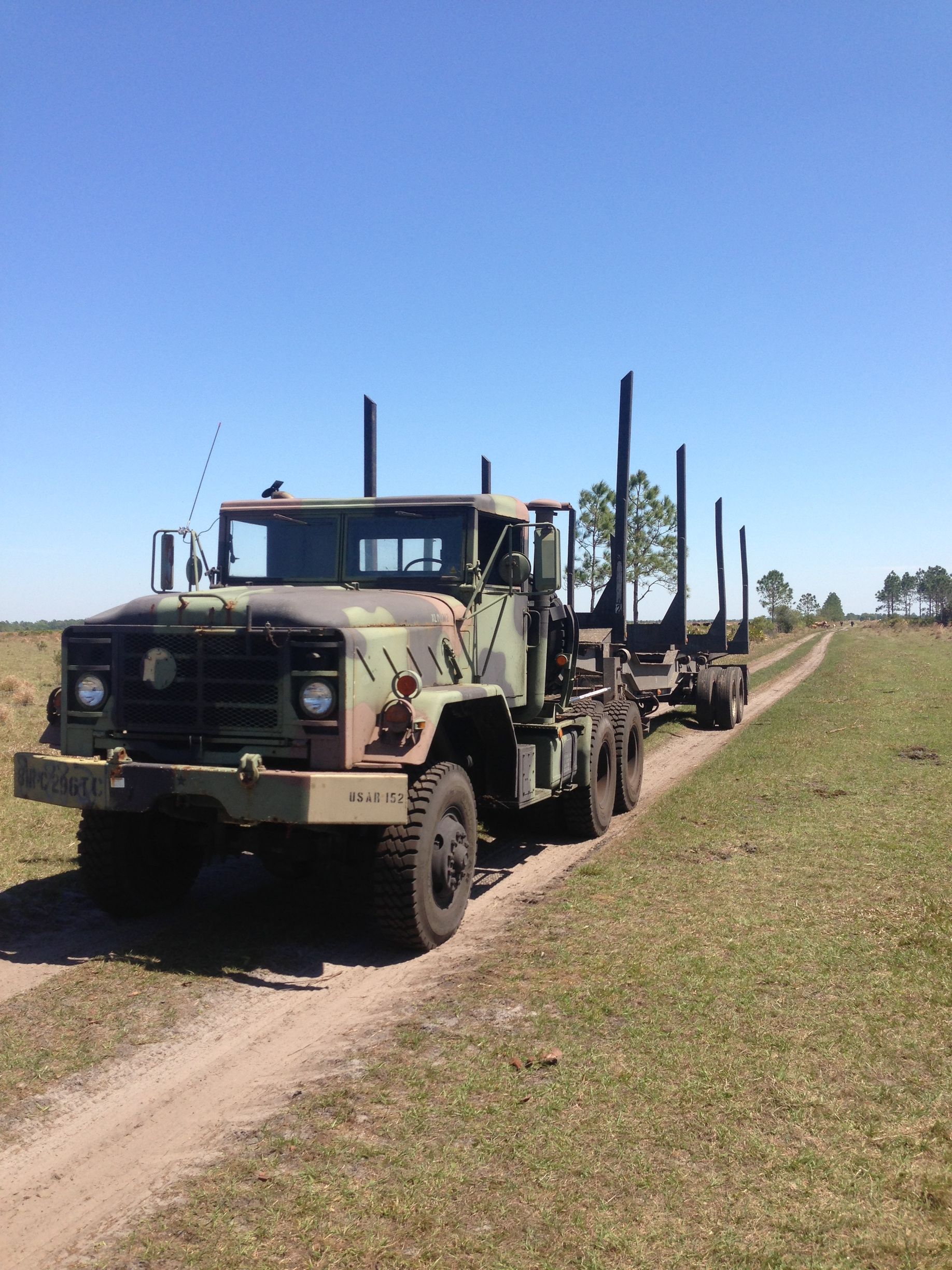 A military truck is driving down a dirt road