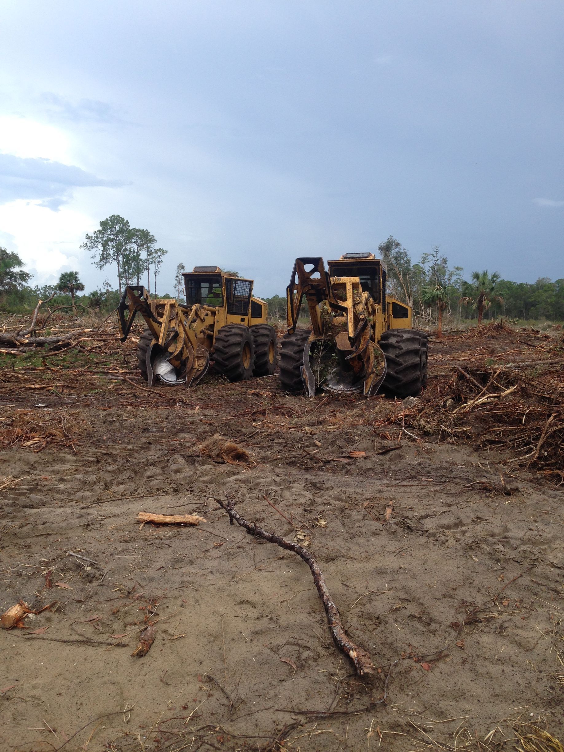 Two bulldozers are parked in a dirt field
