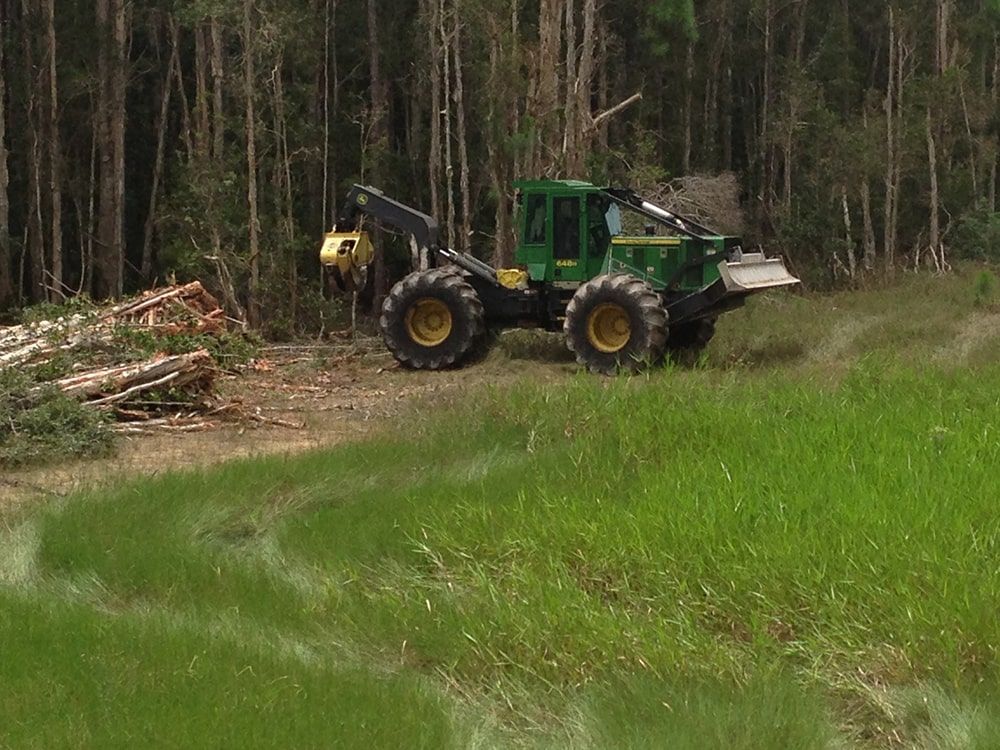 A green and yellow tractor is driving through a grassy field.