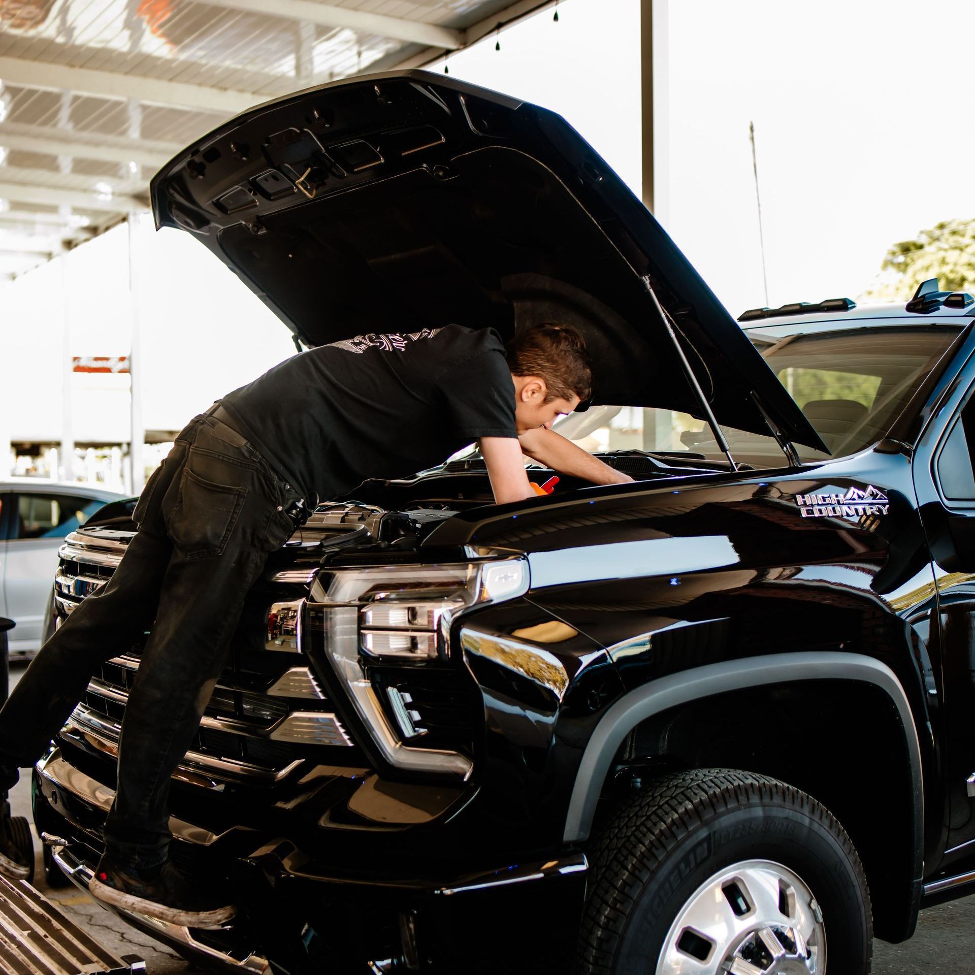 A man with a beard is working on a car with the hood open