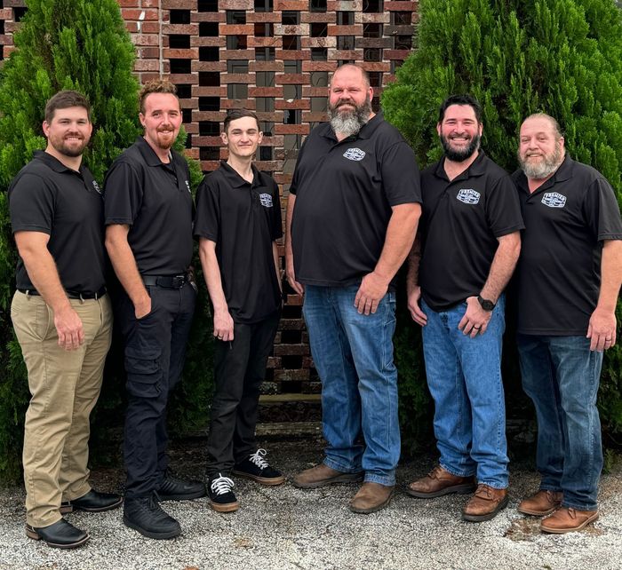 A group of men standing next to each other in front of a brick wall