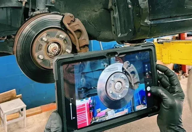 A person is holding a tablet with a picture of a brake disc on it.