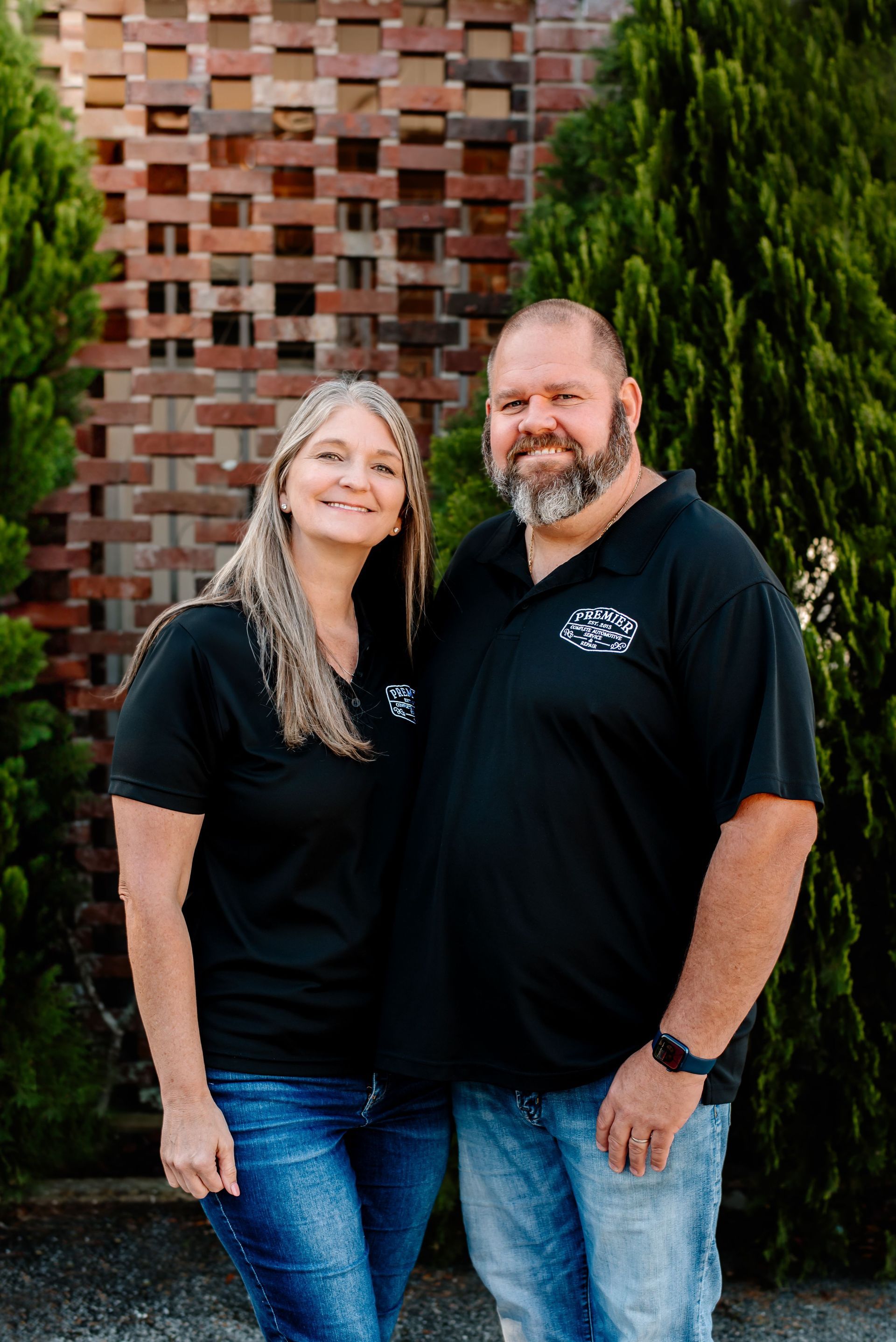 A man and a woman are posing for a picture in front of a brick wall.