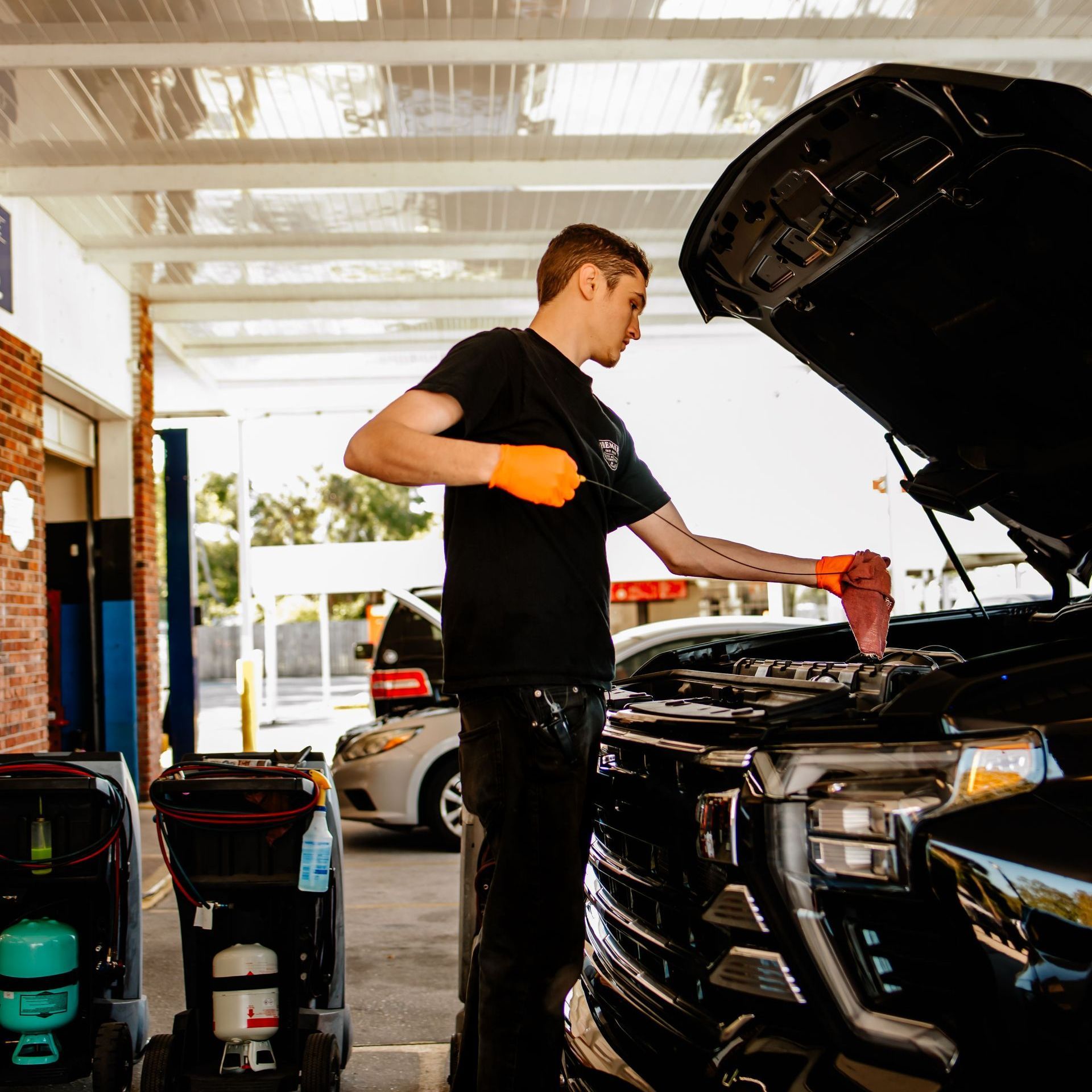 A car is on a lift in a garage while a man looks at his phone