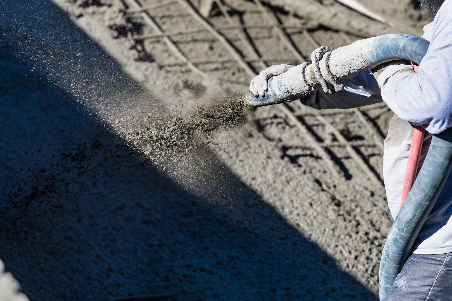 Worker guiding a pump hose to place wet concrete over rebar. Worker guiding a pump hose to place wet concrete over rebar.