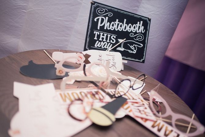 Wedding table decor with glasses, chalkboard sign, and cake topper on a purple tablecloth